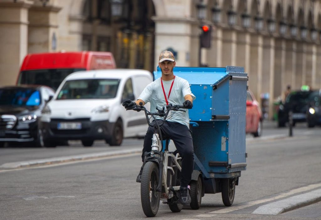 Repartidor amb bicicleta de càrrega en un entorn urbà, exemple de mobilitat sostenible